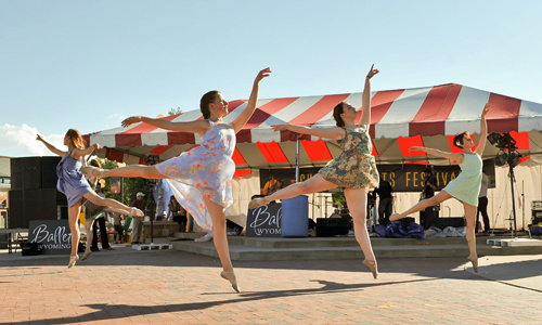 Four dancers jumping in front of a tent