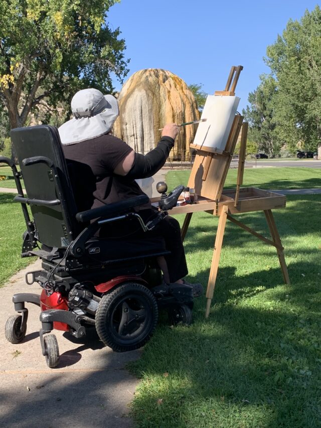 Painter in a wheelchair painting the Teepee Fountain in Hot Springs State Park